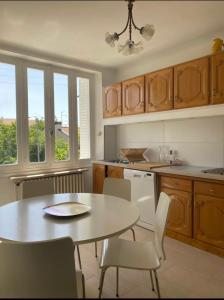 uma cozinha com mesa e cadeiras e algumas janelas em Le Jacques rose em Aubière