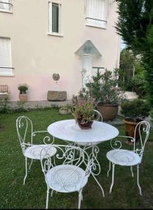 una mesa blanca y sillas en un patio en Le Jacques rose en Aubière