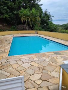 a swimming pool with a stone floor and blue water at Casa Aconchegante em Serra Negra in Serra Negra