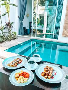 three plates of food on a table next to a swimming pool at Private Pool Cabanas AC - Angam Villas Hikkaduwa in Hikkaduwa