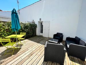 un patio con mesa, sillas y sombrilla en Le Petit Malo - Sudio avec terrasse et parking privé, en La Rochelle