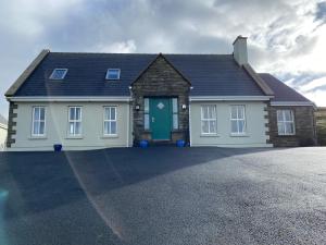 a house with a green door on a driveway at The Cliffs of Moher House, Doolin in Doolin