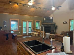 a kitchen with a sink and a living room at Nantahala Nook, cabin w/hot tub,game room, & wifi in Bryson City