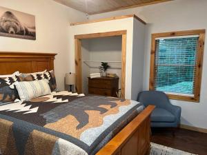 1 dormitorio con 1 cama, 1 silla y 1 ventana en Nantahala Nook, cabin w/hot tub,game room, & wifi en Bryson City