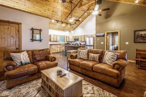 a living room with leather couches and a table at Nantahala Nook, cabin w/hot tub,game room, & wifi in Bryson City