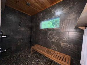 a bathroom with a wooden bench and a window at Nantahala Nook, cabin w/hot tub,game room, & wifi in Bryson City +47 photos