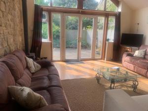 sala de estar con sofá y mesa de cristal en Stunning Barn Conversion next to Horse Field sleeps 10, en Morpeth