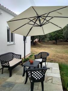 un patio con 2 sillas y una mesa con sombrilla en Rizaki Cottage in Nafpaktos, en Nafpaktos