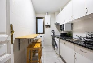 eine kleine Küche mit weißen Schränken und einem Waschbecken in der Unterkunft Antón Rooms in Madrid