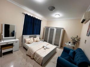 - une chambre avec un lit et un canapé bleu dans l'établissement Retreat Haven, à Al-Aïn