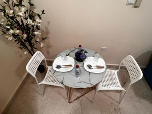 una mesa de cristal con 3 sillas y un jarrón con flores en Retreat Haven, en Al Ain