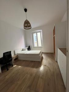 a white bedroom with a bed and a window at Collie’s place in Koper