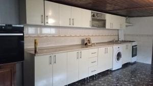 eine Küche mit weißen Schränken und einer Waschmaschine und einem Trockner in der Unterkunft Casuta de sub munte in Buzău