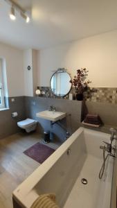 een badkamer met een bad, een wastafel en een spiegel bij Ferienwohnung Rote Leite in Ebensfeld