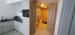 a kitchen with white cabinets and a black refrigerator at Design Apartment in Bolszewo