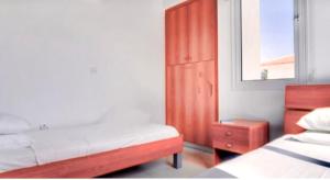 a bedroom with two beds and a wooden cabinet at Villa millie Cyprus in Protaras