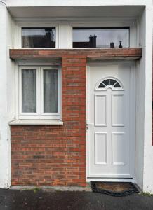 a brick house with a white door and two windows at Appartement Cosy et fonctionnel 4 personnes in Le Havre