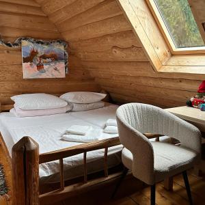 een slaapkamer met een bed en een stoel in een hut bij Будинок Художника in Synevyrsʼka Polyana