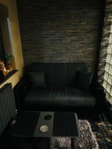 Lovely 1 bedroom flat in a 2 ground floor house في كرايوفا: أريكة سوداء في غرفة معيشة مع طاولة
