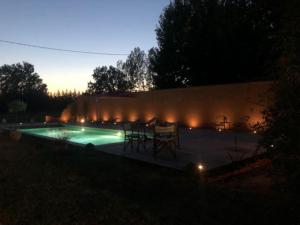 uma piscina à noite com cadeiras e luzes em Spacieux Mas Provençale em Sarrians