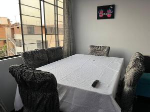 una mesa y sillas blancas en una habitación con ventana en Espacio para ti y tu familia, en Lima