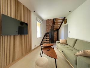 uma sala de estar com um sofá e uma televisão na parede em Appartement Neuf et Design em Camarsac