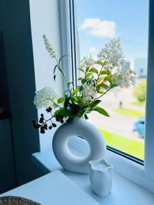 un jarrón blanco con flores sentado en el alféizar de la ventana en Ilmarise Apartment en Viljandi