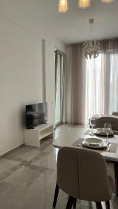 ein Wohnzimmer mit einem Tisch, Stühlen und einem TV in der Unterkunft DELMAR Residence in Becici