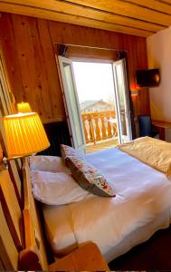 1 dormitorio con 1 cama con ventana y lámpara en Hôtel des Skieurs en Le Sappey-en-Chartreuse