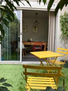 einen gelben Tisch und zwei Stühle auf einer Terrasse in der Unterkunft Apartment in a charming house in Asnières-sur-Seine