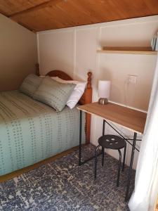 a small bedroom with a bed and a desk at Cozy Glamping Cabins in Motueka