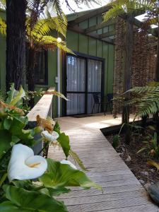 einen hölzernen Gehweg in einem Garten mit Pflanzen in der Unterkunft Cozy Glamping Cabins in Motueka