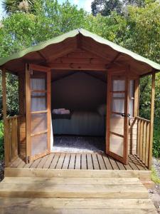 a wooden gazebo with a couch in it at Cozy Glamping Cabins in Motueka