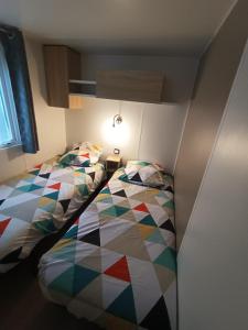 a bedroom with two beds with a colorful comforter at mobil home 3 chambres 152 in Pont-Aven