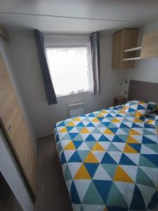 a bedroom with a colorful bed with a window at mobil home 3 chambres 152 in Pont-Aven