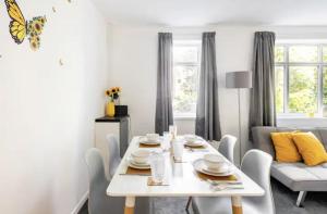 a white dining room with a white table and chairs at Flat in leafy Sale, Manchester in Sale