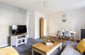 a living room with a couch and a tv and a table at Flat in leafy Sale, Manchester in Sale