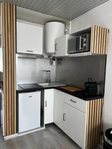 a kitchen with white cabinets and a microwave at Coquet studio au centre port du Cap d'Agde in Cap d'Agde