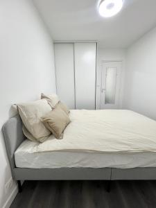 Dormitorio blanco con cama con sábanas y almohadas blancas en Appartement récemment rénové à 1min du métro, en Créteil