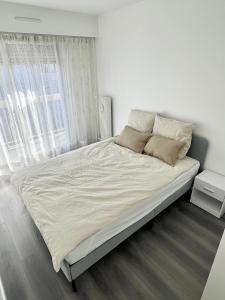 1 dormitorio con 1 cama grande con sábanas y almohadas blancas en Appartement récemment rénové à 1min du métro, en Créteil