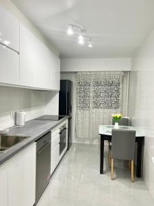 una cocina con armarios blancos y una mesa con una silla en Appartement récemment rénové à 1min du métro, en Créteil