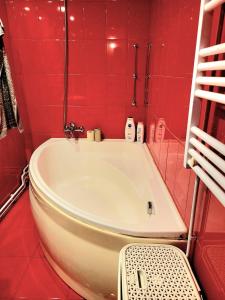 a red tiled bathroom with a white bath tub at Apartament Velana in Reşiţa