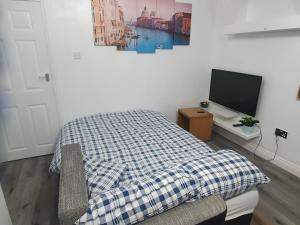 - une chambre avec un lit et une télévision sur un bureau dans l'établissement Femros Apartments, 15mins to city center., à Smethwick
