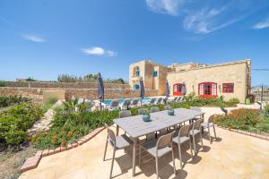 eine Terrasse mit einem Tisch und Stühlen sowie ein Gebäude in der Unterkunft Gaia Holiday Home in San Lawrenz