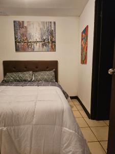 1 dormitorio con 1 cama y una pintura en la pared en cerca aeropuerto tobias bolaños en San José