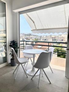 una mesa y sillas blancas en una habitación con ventana en Majestic Apartment, en Cannes