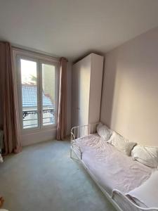 a bedroom with a bed and a large window at Dupleix Boulogne plein centre in Boulogne-Billancourt
