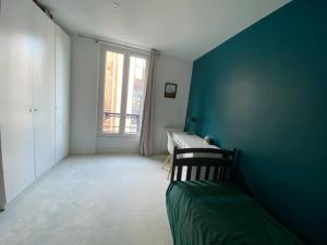 a room with a blue wall with a bed and a window at Dupleix Boulogne plein centre in Boulogne-Billancourt