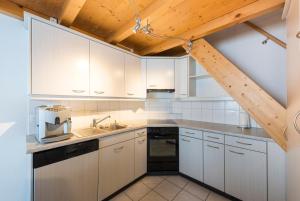 uma cozinha com armários brancos e um tecto de madeira em Obere Frutt 9 em Frutt