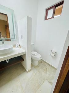ein Badezimmer mit einem WC, einem Waschbecken und einem Spiegel in der Unterkunft Villas Ecuestre Hotel Tepoztlán in Tepoztlán